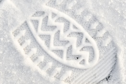 Close-up of a shoe print in the snow, top view of a boot footprint photo