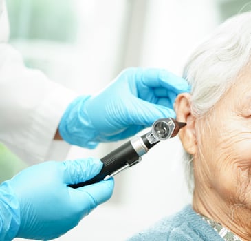 Otolaryngologist or ENT physician doctor examining senior patient ear with otoscope, hearing loss problem. photo