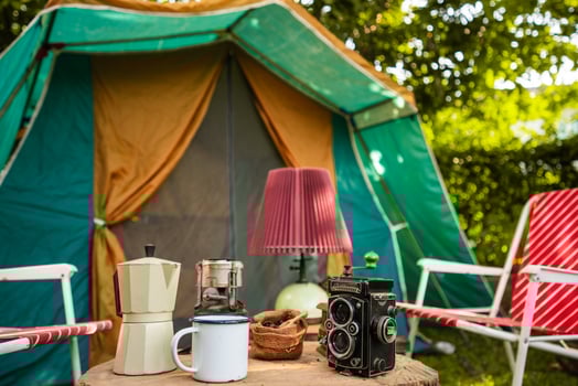 selective focus of vintage coffee set on the old wooden table In front of the retro cabin tent, Antique oil lamp, retro chairs, Group of camping tents, and soft focus. photo