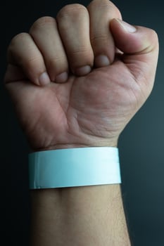 Blue paper wristband mockup on persons arm. Empty adhesive bangle wristlet sticker on male hand. photo