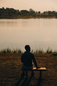 Silhouette of young man sits praying alone at the top of the mountain at sunset with beautiful natural sunlight. photo