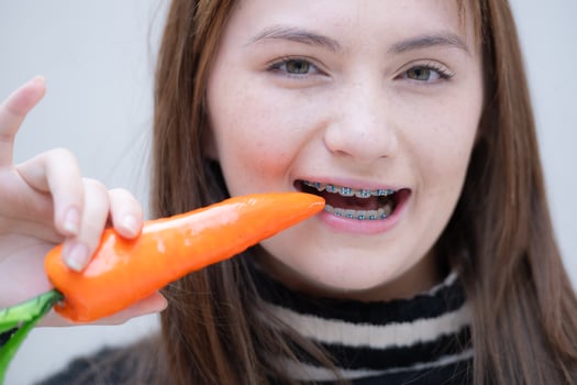 Portrait of Teenage girl eating carrot in her teeth. photo