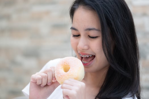 Portrait of Asian woman eating donut in the kitchen at home photo