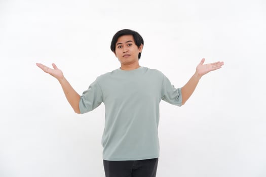 A young Asian man raises his hand with a confused and clueless expression photo