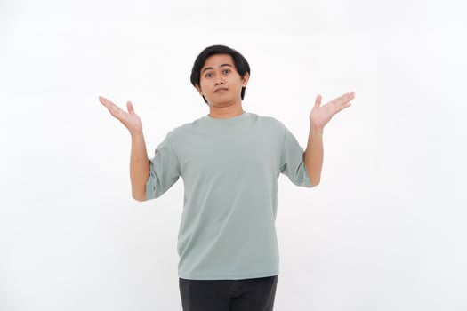 A young Asian man raises his hand with a confused and clueless expression photo