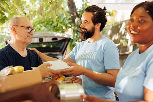 Close-up of multiethnic volunteers, including a smiling woman, distribute donations of food to the needy, offering help and hope to homeless people. Caring charity workers aiding the less privileged. photo