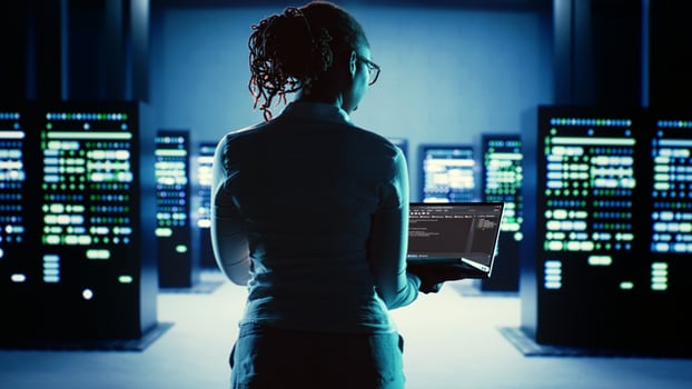 Dilligent worker running code on laptop, troubleshooting and upgrading high tech workplace infrastructure designed to accommodate server components, networking systems and storage arrays photo
