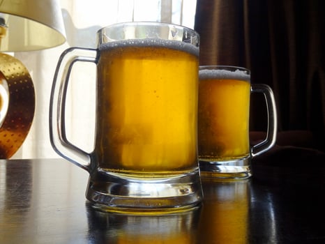 Full draft beer tankards on the wooden table photo