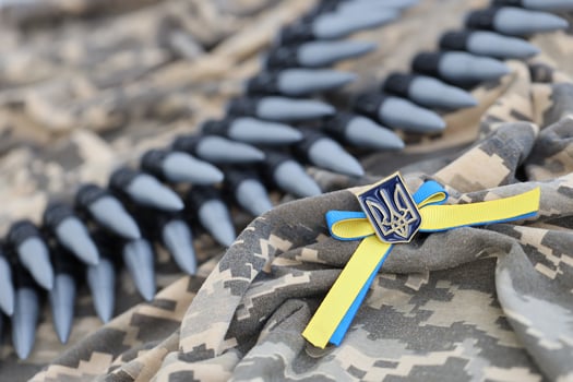 Ukrainian symbol and a machine gun belt on the camouflage uniform of a Ukrainian soldier. The Concept of war in Ukraine, patriotism and protecting your country from occupiers photo