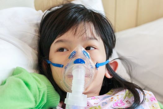 Sick little asian girl inhalation with nebulizer for respiratory treatment photo
