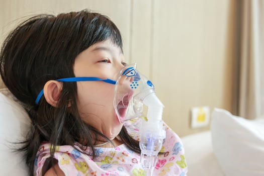 Sick little asian girl inhalation with nebulizer for respiratory treatment photo