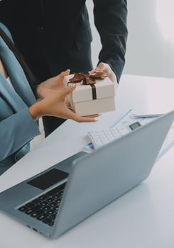 Young businessman giving his colleague present in office. Young man surprise beautiful businesswoman in office. photo