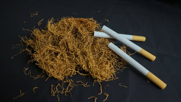 cut tobacco leaves and handmade cigarettes on black background photo