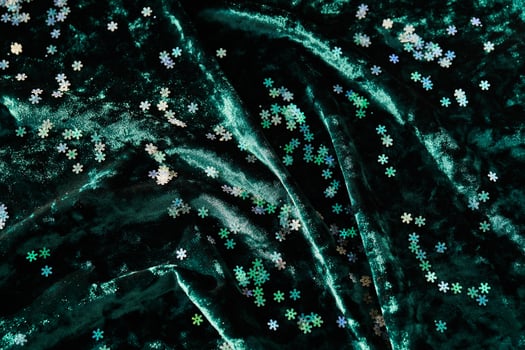 Snowflake shaped confetti on green velvet. Christmas background. photo