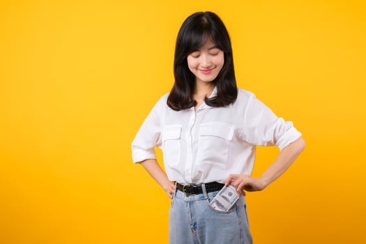 Captivating image of Asian young woman wearing white shirt and denim jeans, confidently holding cash from her shirt pocket. Fashion meets financial empowerment. Perfect for finance and fashion themes. photo