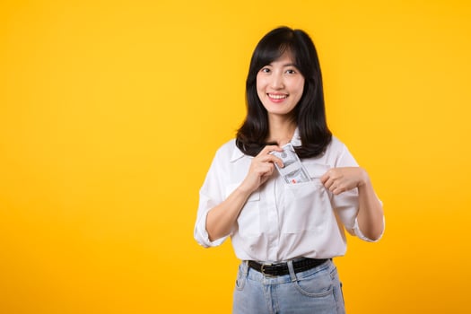 Captivating image of Asian young woman wearing white shirt and denim jeans, confidently holding cash from her shirt pocket. Fashion meets financial empowerment. Perfect for finance and fashion themes. photo