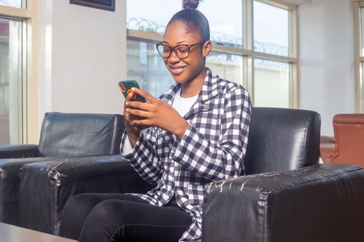 Happy female checking smart phone sitting on a couch in the living room at home photo