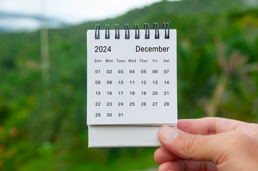 Hand holding December 2024 white calendar with nature background. Holiday and calendar concept photo