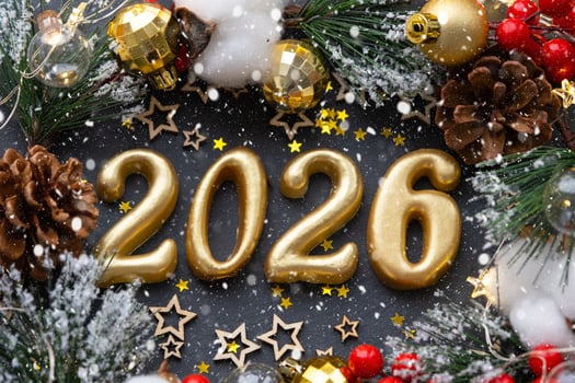 The golden figures 2026 made of candles on a black stone slate background are decorated with a festive decor of stars, sequins, fir branches, balls and garlands. Greeting card, happy New Year. photo