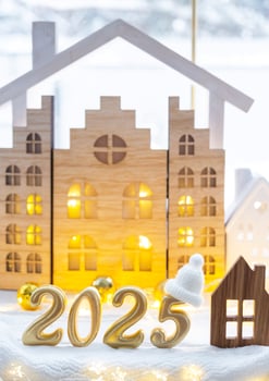 Golden figures number 2025 and tiny home on background of cozy windows of a house with warm light with festive decor of stars,snow and garlands. Greeting card, Happy New Year, cozy home photo