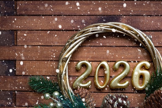 Happy New Year golden numbers 2026 on cozy festive brown wooden background with sequins, snow, lights of garlands. Greetings, postcard. Calendar, cover photo