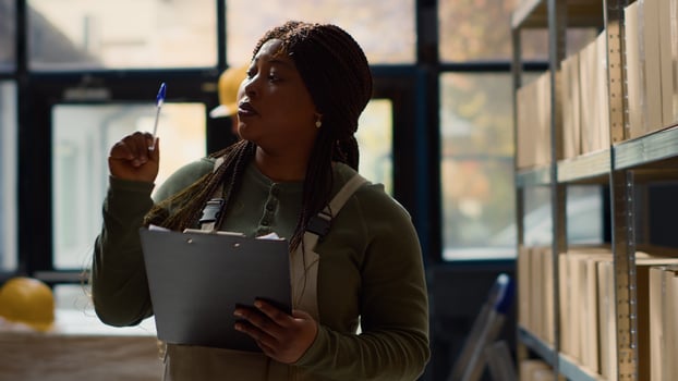 BIPOC warehouse inspector performing inventory audit, keeping quality standards high. Productive expert in distribution center looking at parcels ready to be shipped, crosschecking delivery info photo