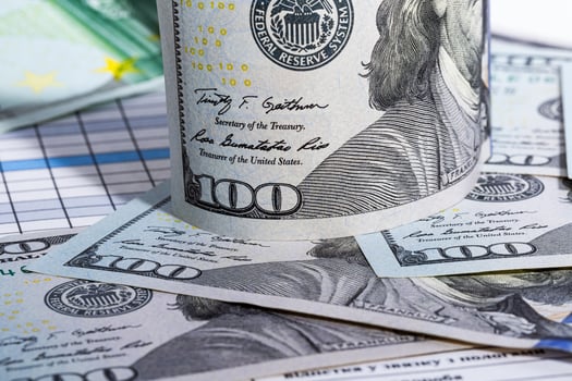 A Stack of Hundred Dollar Bills. A roll of hundred dollar bills sitting on top of a pile of hundred dollar bills photo