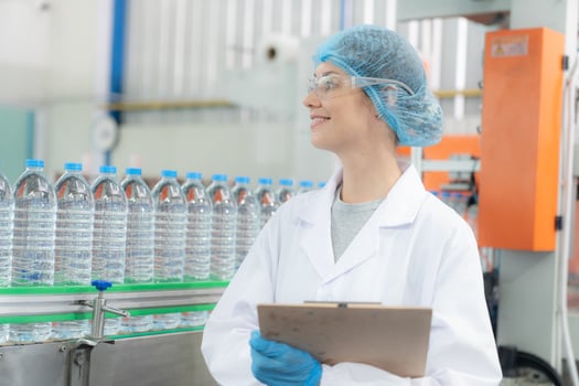 Young happy woman worker in factory checking water gallons before shipment. photo