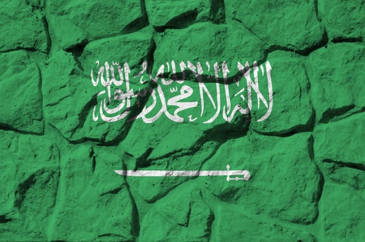 Saudi Arabia flag depicted in paint colors on old stone wall closeup. Textured banner on rock wall background photo