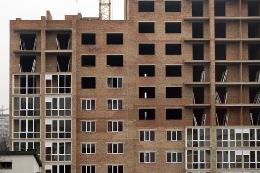 View of a large construction site with buildings under construction and multi-storey residential homes. Tower cranes in action on blue sky background. Housing renovation concept photo