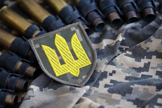 Ukrainian army symbol on machine gun belt lies on ukrainian pixeled military camouflage photo