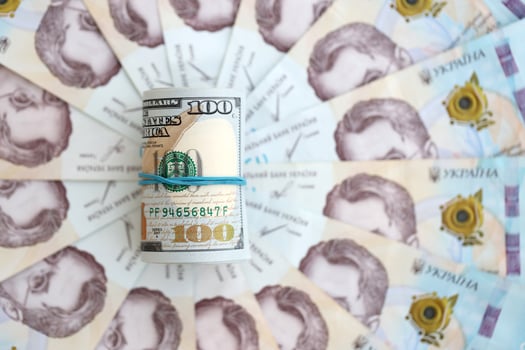 Bunch of hundred US dollar bills lies on many banknotes of ukrainian hryvnias. Economical default, crisis and devaluation of ukrainian national currency photo