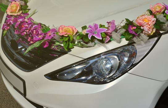 A detailed photo of the hood of the wedding car, decorated with many different flowers. The car is prepared for a wedding ceremony