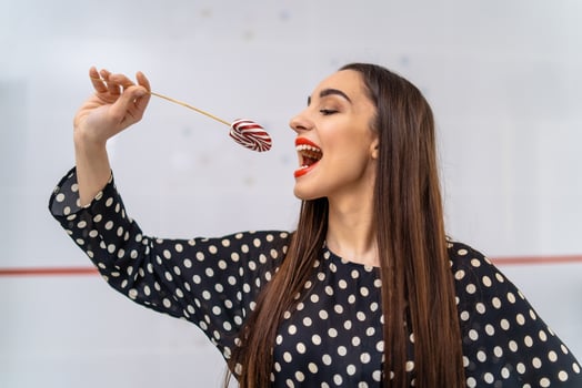 A Woman Enjoying a Lollipop. A woman holding a lollipop up to her mouth photo