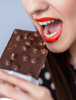 Woman Enjoying a Chocolate Bar. A woman eating a chocolate bar with her mouth open photo