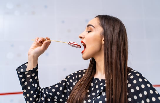 A Woman Enjoying a Candy Cane. A woman eating a candy cane with her mouth wide open photo