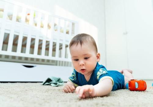 Baby Engaged in Playtime on the Floor. A baby laying on the floor playing with a toy photo