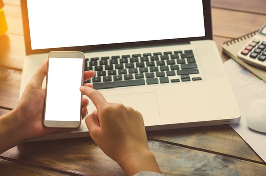 Hand holding smartphone for working on laptop photo