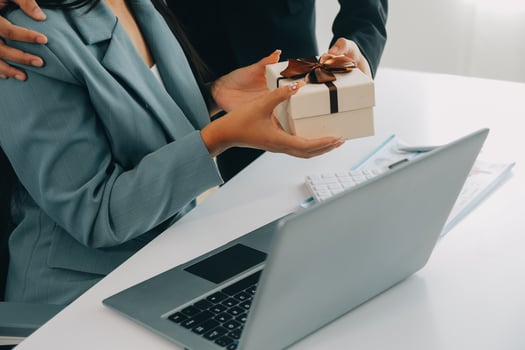 Young businessman giving his colleague present in office. Young man surprise beautiful businesswoman in office. photo
