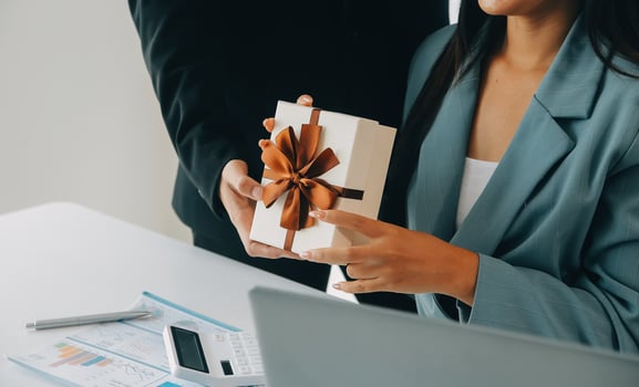 Young businessman giving his colleague present in office. Young man surprise beautiful businesswoman in office. photo