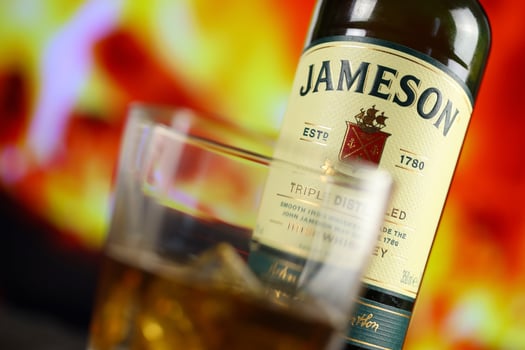 KYIV, UKRAINE - MAY 4, 2022 Jameson original alcohol bottle on wooden table with red fireplace photo