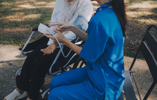 nurse with elderly man in wheelchair at park photo