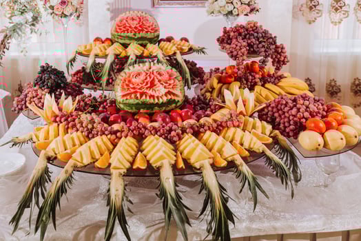 table with various fruit decorations. Watermelon carving, pineapple slices, grapes, orange photo