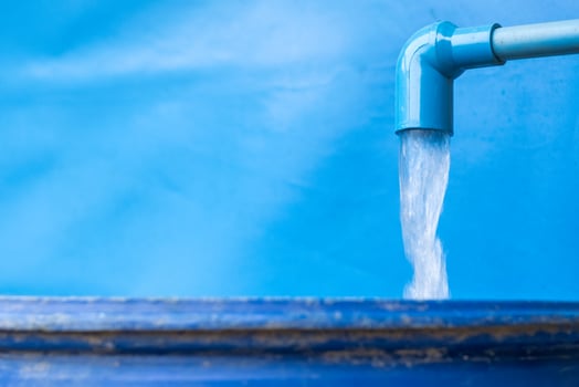 Blue pvc pipe with flowing water in bucket photo