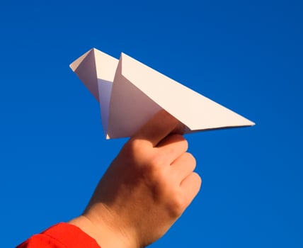 White paper airplane in hand against the sky. A symbol of freedom on the Internet photo