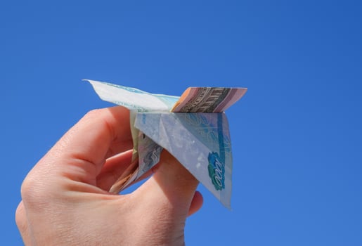 Denominations of Russian money, folded in the airplane against the blue sky in hand photo