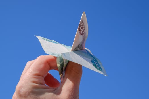 Denominations of Russian money, folded in the airplane against the blue sky in hand photo