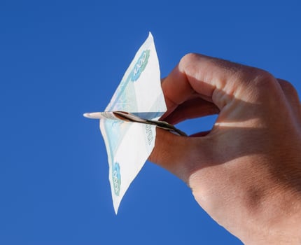 Denominations of Russian money, folded in the airplane against the blue sky in hand photo