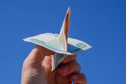Denominations of Russian money, folded in the airplane against the blue sky in hand photo