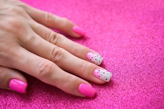 Beautiful female hands with manicure on a pink shiny background. Tinted nail design. Summer manicure. Copy space. photo